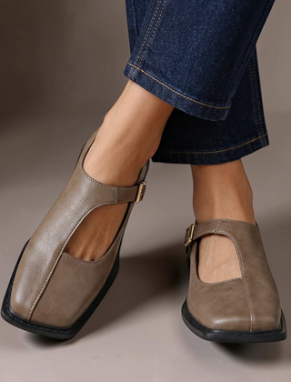 Rosalie ash gray leather-look flats with a classic T-strap design and square toe worn with blue jeans.