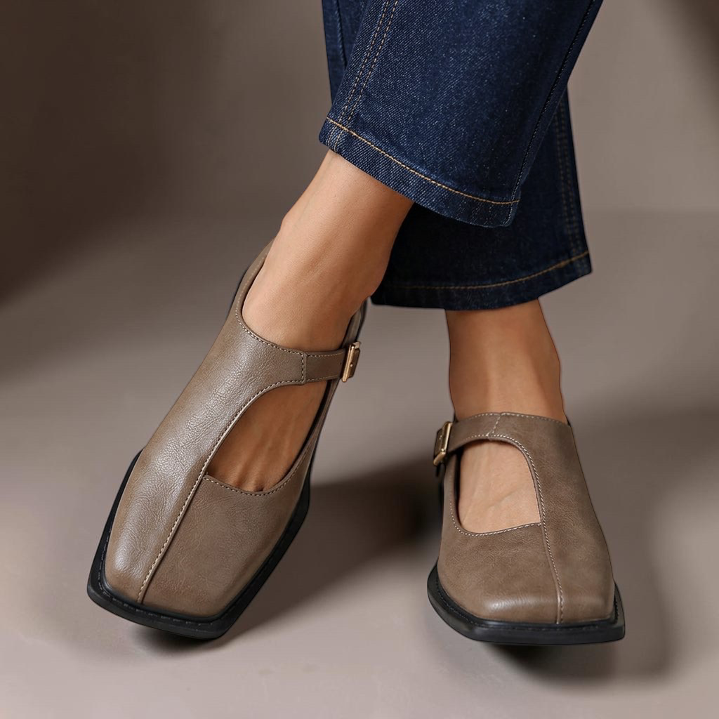 Rosalie ash gray leather-look flats with a classic T-strap design and square toe worn with blue jeans.